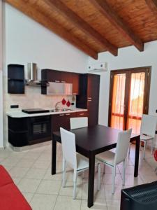 eine Küche mit einem schwarzen Tisch und weißen Stühlen in der Unterkunft Casa Ponente e Casa Levante in Buggerru