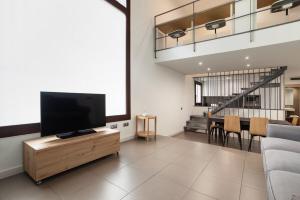 Modern and bright 4BD triplex in Paralel! في برشلونة: غرفة معيشة مع تلفزيون بشاشة مسطحة على طاولة خشبية