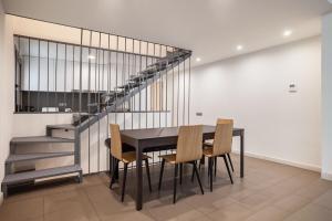 comedor con mesa, sillas y escaleras en Modern and bright 4BD triplex in Paralel!, en Barcelona