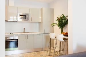 kuchnia z białymi szafkami, zlewem i stołkami w obiekcie Perfectly located 4-bed 4-bath apartment in Barcelona 2-1 w Barcelonie