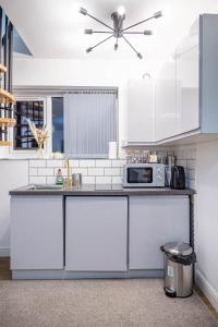 uma cozinha com armários brancos e um micro-ondas em Bv Homely Aparthotel Almondbury Huddersfield em Huddersfield