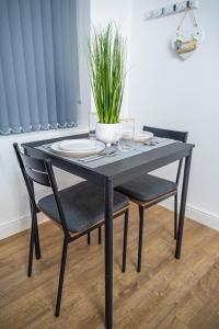 uma mesa preta com duas cadeiras e uma planta sobre ela em Bv Homely Aparthotel Almondbury Huddersfield em Huddersfield