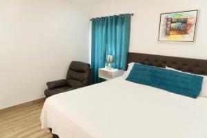 a bedroom with a large bed and a chair at Micro Hotel Rio de Piedras in San Pedro Sula