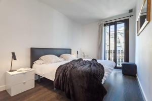 a white bedroom with a large bed and a window at 3-bedroom penthouse with terrace in Eixample in Barcelona