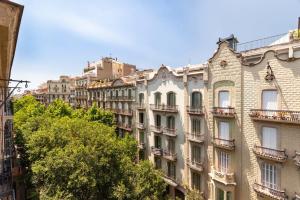 un edificio alto con árboles delante de él en 3-bedroom penthouse with terrace in Eixample, en Barcelona