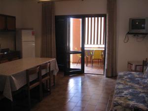 eine Küche und ein Esszimmer mit einem Tisch, einem Tisch und Stühlen in der Unterkunft Borgo Spiaggia Isola Rossa in Isola Rossa