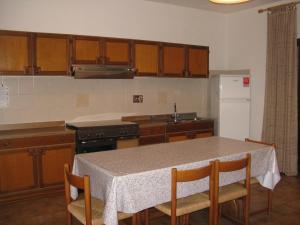 una cucina con tavolo, sedie e piano cottura di Borgo Spiaggia Isola Rossa a Isola Rossa