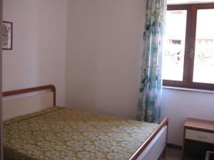 Schlafzimmer mit einem Bett und einem Fenster in der Unterkunft Borgo Spiaggia Isola Rossa in Isola Rossa