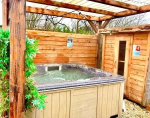 a hot tub in a wooden building with a pergola at Wellness bungalow with jacuzzi &sauna&private garden near Amsterdam in Vijfhuizen