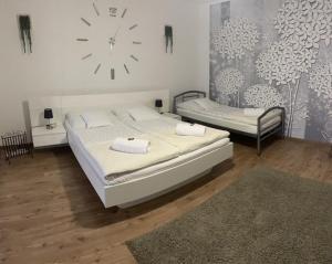 um quarto com duas camas e um relógio na parede em Mini Vendégház Budaörs em Budaörs