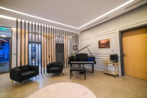 a living room with a piano and two chairs at Diamond Jumeirah Garden City 1BR Apt in Dubai