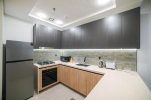 a kitchen with wooden cabinets and a refrigerator at Diamond Jumeirah Garden City 1BR Apt in Dubai