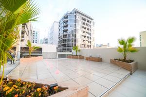 a rooftop patio with palm trees and a building at Diamond Jumeirah Garden City 1BR Apt in Dubai