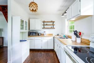 a white kitchen with wooden floors and white cabinets at Cozy Cottage on wooded lot with Hot Tub & Fire Pit in Front Royal