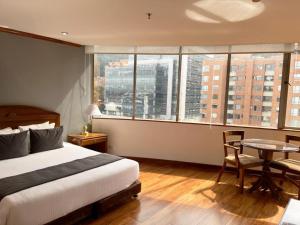 a bedroom with a bed and a table and windows at Hotel Bogotá Regency Usaquén in Bogotá