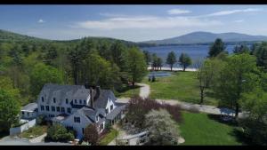 an aerial view of a large house with a lake at Inn at Pleasant Lake in New London