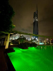 吉隆坡的住宿－Casa Residency Apartment，绿色泳池,在晚上有一座建筑背景
