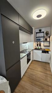 a kitchen with white cabinets and a black refrigerator at Apartament Anastazja FREE PARKING in Krakow