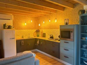 una cucina con armadi grigi e frigorifero bianco di In de bocht - Hottub Sauna a Gemonde
