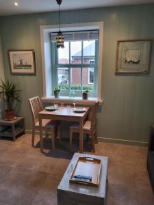 Berkhout的住宿－B & B De Tocht，客厅配有桌椅和窗户。