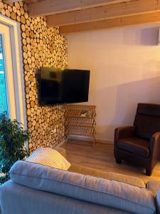 In de bocht - Hottub Sauna في Gemonde: غرفة معيشة مع أريكة وتلفزيون بشاشة مسطحة