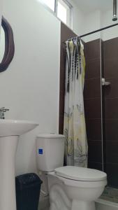 a bathroom with a toilet and a shower curtain at Hostal Los Arhuacos in Santa Marta