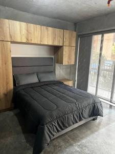 a bedroom with a large black bed with wooden cabinets at Apartaestudio tipo loft nuevo in Medellín