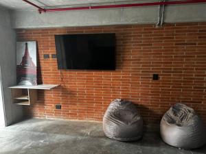 a brick wall with a flat screen tv and two bean bags at Apartaestudio tipo loft nuevo in Medellín