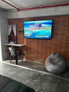 a room with a tv on a brick wall at Apartaestudio tipo loft nuevo in Medellín