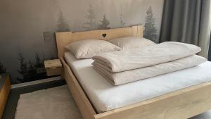 Una cama con sábanas blancas y almohadas. en Loder Lodge, en Sankt Jakob in Haus
