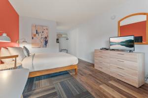 Dormitorio con cama y tocador con TV en Okanagan Lakefront Resort en Penticton