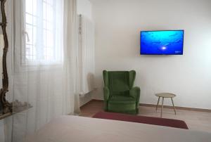 Cette chambre comprend une chaise verte et une télévision murale. dans l'établissement Dimora del Castello - Comfort & Privacy, à Castel Maggiore