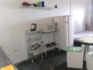 a small kitchen with a shelf with a microwave at Quarto e banheiro particular in Taboão da Serra