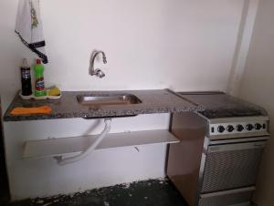 uma cozinha com um lavatório e um fogão em Quarto e banheiro particular em Taboão da Serra