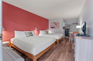 two beds in a room with a red wall at Okanagan Lakefront Resort in Penticton