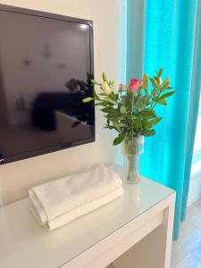 a vase of flowers on a table with a tv at Anamari Apartments in Zadar