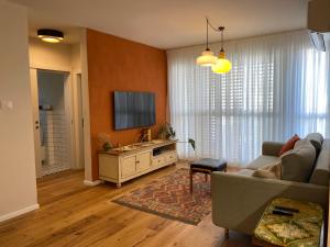 ein Wohnzimmer mit einem Sofa und einem Flachbild-TV in der Unterkunft נופש ליד הים בת גלים in Haifa