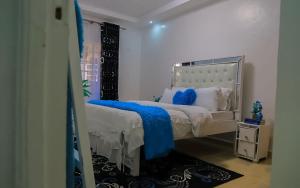 a bedroom with a white bed with a blue blanket at Cade Homes 2 in Narok