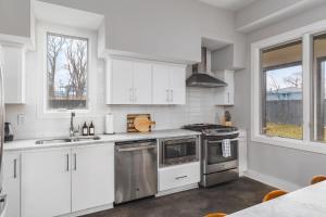 una cocina con armarios blancos y electrodomésticos de acero inoxidable en Modern Luxury Rooftop Deck, 3 mi to Downtown, en Nashville