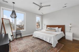a white bedroom with a bed and a large window at Modern Luxury Rooftop Deck, 3 mi to Downtown in Nashville