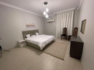 a white bedroom with a bed and a table at Fully furnished family house in Al Madinah