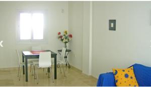 ein Esszimmer mit einem Tisch und einer Vase aus Blumen in der Unterkunft Dúplex en primera línea Playa Faro in Garrucha
