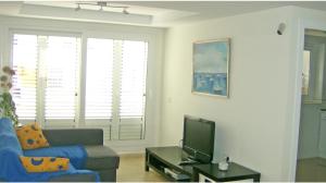 ein Wohnzimmer mit einem Sofa und einem TV in der Unterkunft Dúplex en primera línea Playa Faro in Garrucha
