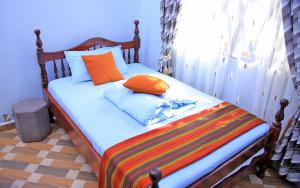 a bed with orange and blue pillows on it at Heavenly Royalz Farm Fortportal in Njara