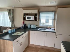 a kitchen with white cabinets and a sink and a microwave at KINGFISHER COURT 2 Tattershall lakes with hot tub in Tattershall