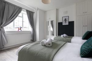 - une chambre avec 2 lits et des serviettes dans l'établissement Stylish & Spacious 3bed in Putney, à Londres