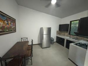 a kitchen with a stainless steel refrigerator and a table at Amazilia Guesthouse in Liberia