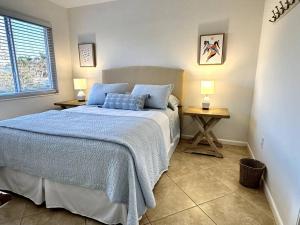 una camera da letto con un letto con una coperta blu e due tavoli di Renovated Cozy Apartment in Naples (1.4 miles from the beach) a Naples