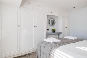 a white bedroom with a bed and a mirror at Stylishly decorated 3 bed house presented by Our Home Short Stays comfortable beds with crisp linen and plenty of outdoor space to enjoy in Bedford
