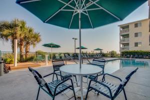 - une table avec des chaises et un parasol à côté de la piscine dans l'établissement Beach Club II 2E - Oceanfront - Windy Hill Section, à Myrtle Beach